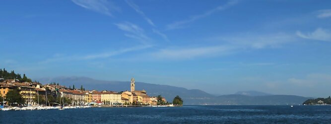 Trip Kanaren beliebte Urlaubsziele am Gardasee -  Mit einer Fläche von 370 km² ist der Gardasee der größte See Italiens. Es liegt am Fuße der Alpen und erstreckt sich über drei Staaten: Lombardei, Venetien und Trentino. Die maximale Tiefe des Sees beträgt 346 m, er hat eine längliche Form und sein nördliches Ende ist sehr schmal. Dort ist der See von den Bergen der Gruppo di Baldo umgeben. Du trittst aus deinem gemütlichen Hotelzimmer und es begrüßt dich die warme italienische Sonne. Du blickst auf den atemberaubenden Gardasee, der in zahlreichen Blautönen schimmert - von tiefem Dunkelblau bis zu funkelndem Türkis. Majestätische Berge umgeben dich, während die Brise sanft deine Haut streichelt und der Duft von blühenden Zitronenbäumen deine Nase kitzelt. Du schlenderst die malerischen, engen Gassen entlang, vorbei an farbenfrohen, blumengeschmückten Häusern. Vereinzelt unterbricht das fröhliche Lachen der Einheimischen die friedvolle Stille. Du fühlst dich wie in einem Traum, der nicht enden will. Jeder Schritt führt dich zu neuen Entdeckungen und Abenteuern. Du probierst die köstliche italienische Küche mit ihren frischen Zutaten und verführerischen Aromen. Die Sonne geht langsam unter und taucht den Himmel in ein leuchtendes Orange-rot - ein spektakulärer Anblick.